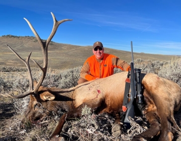 A hunter with his rifle and bull elk